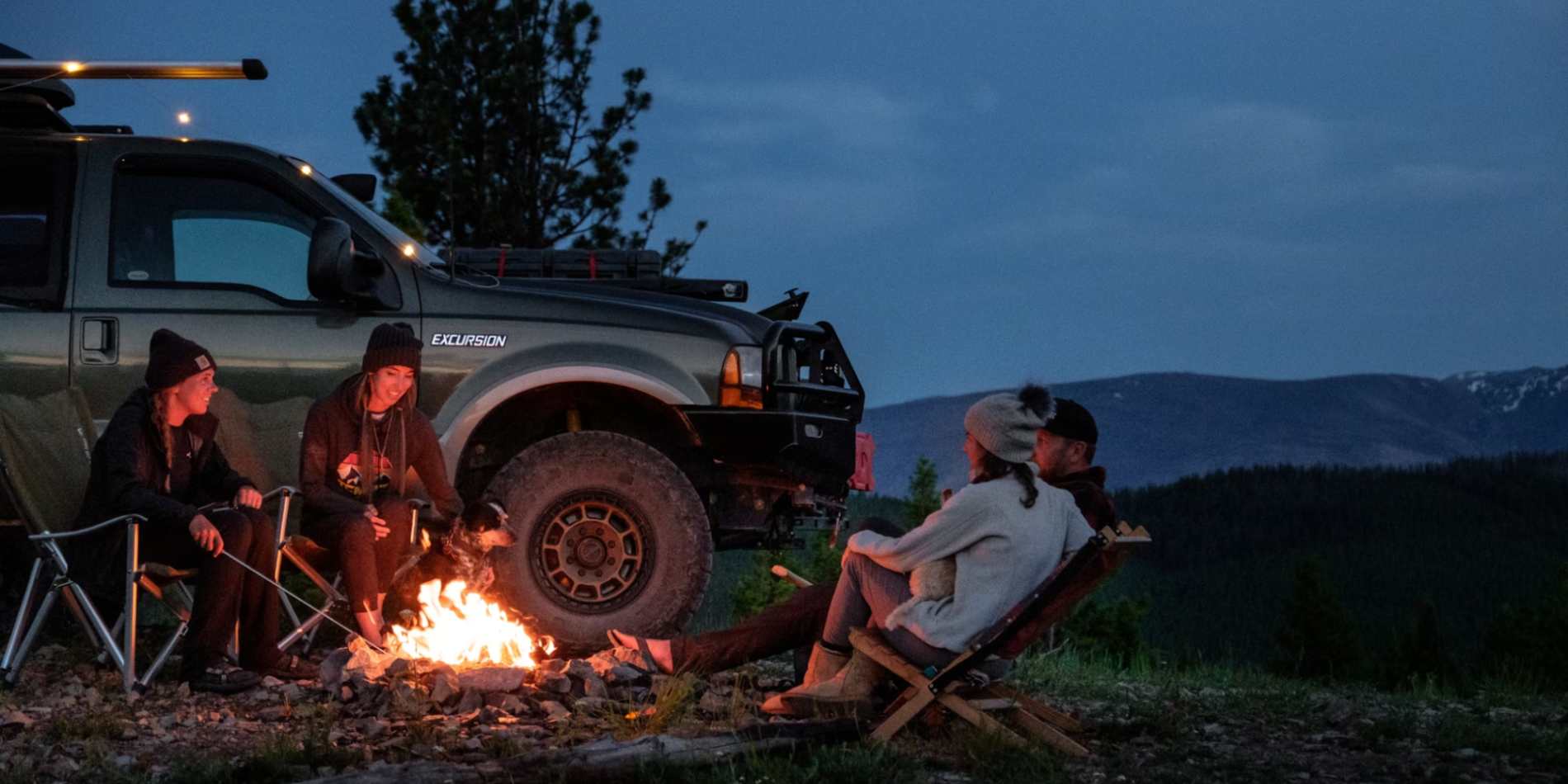 A group of buddies just chilling and sitting around the campfire during their overlanding trip