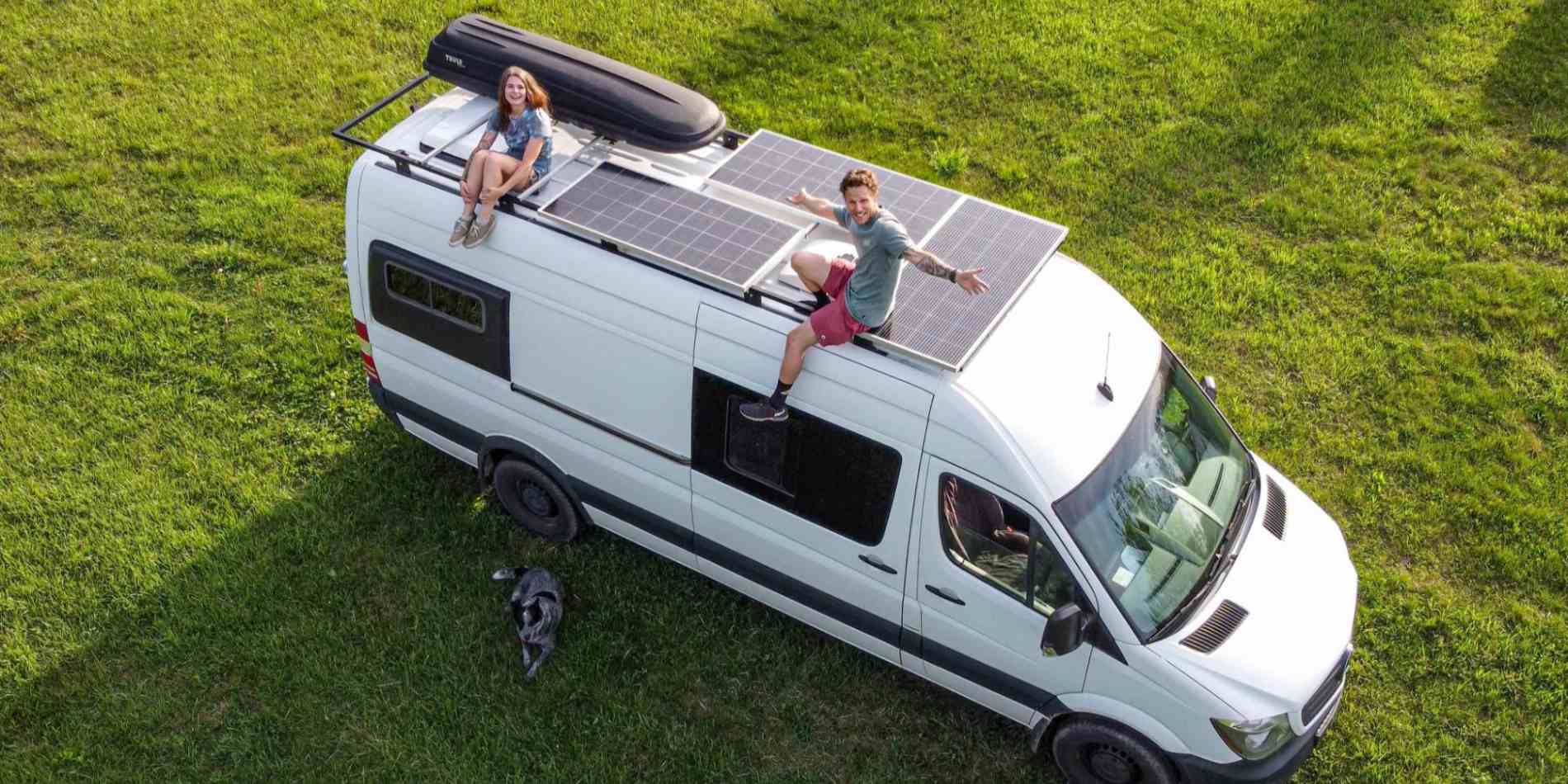 2 people sitting on the RV roof where BougeRV’s solar panels are installed on