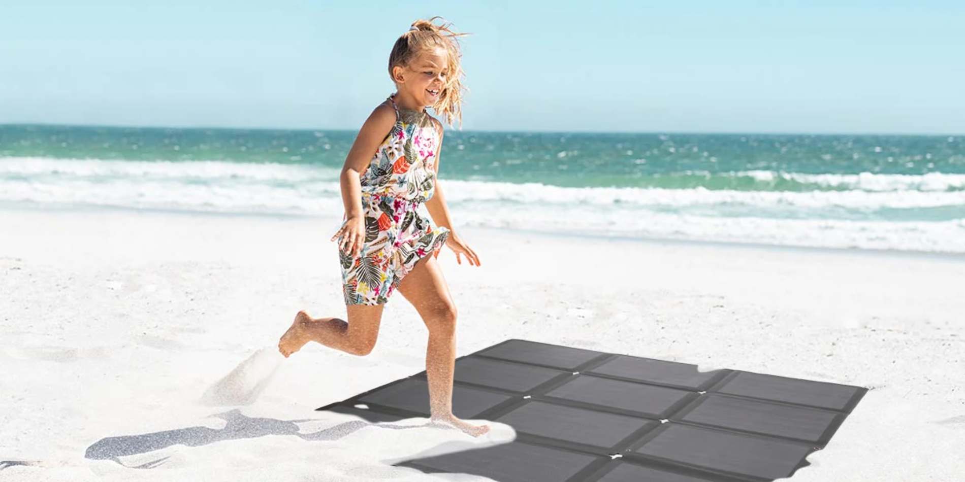 A girl stepping on BougeRV’s folding solar panel on the beach